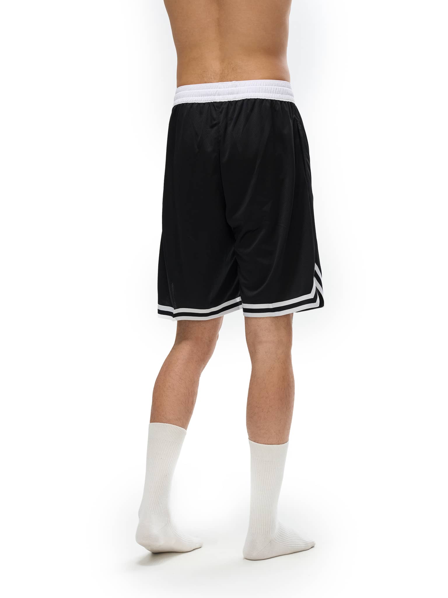 Back view of man wearing FETISHISTO black and white classic basketball shorts with elastic waistband