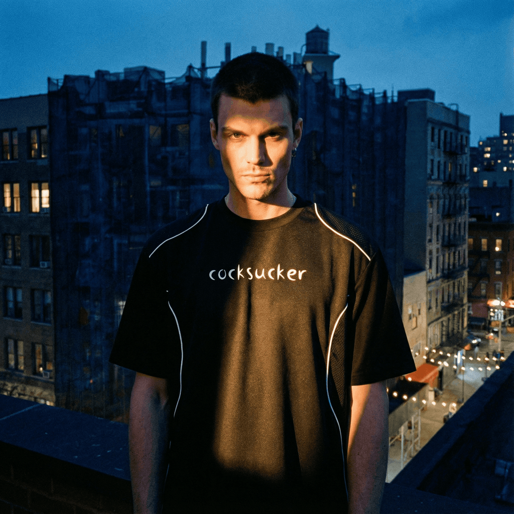 Black contrast piped fetish t-shirt with white piping and bold text worn by male model outdoors at dusk