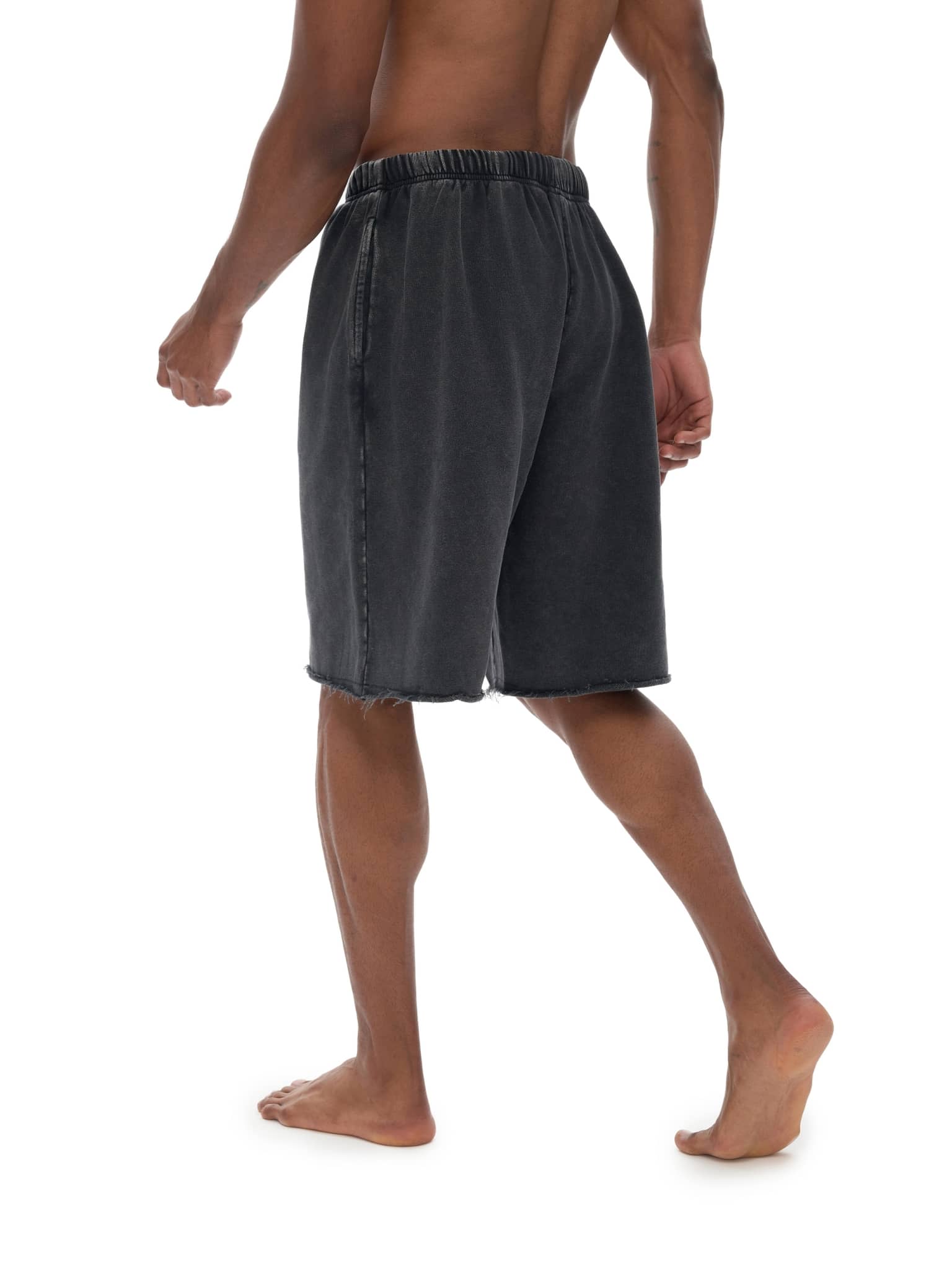 Back view of a man wearing distressed casual black shorts with elastic waistband by FETISHISTO