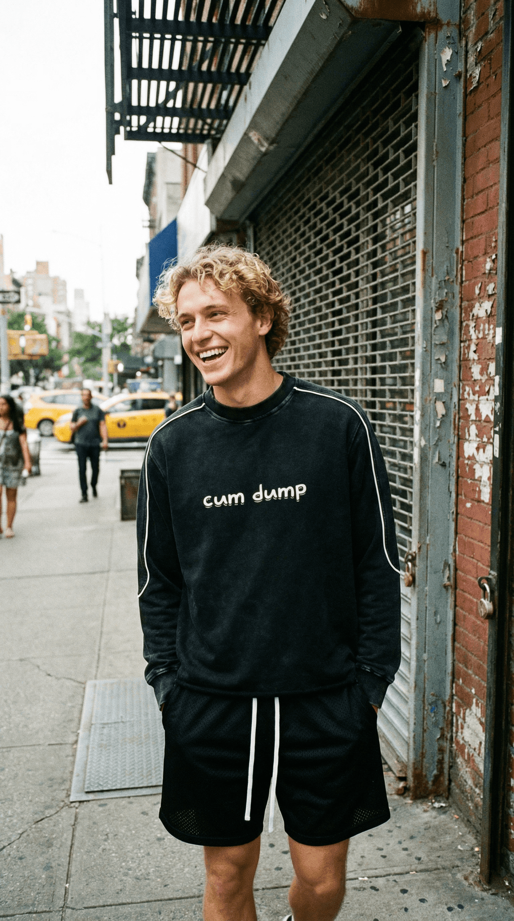 Young man wearing black fetish raw hem sweatshirt with white text on city street