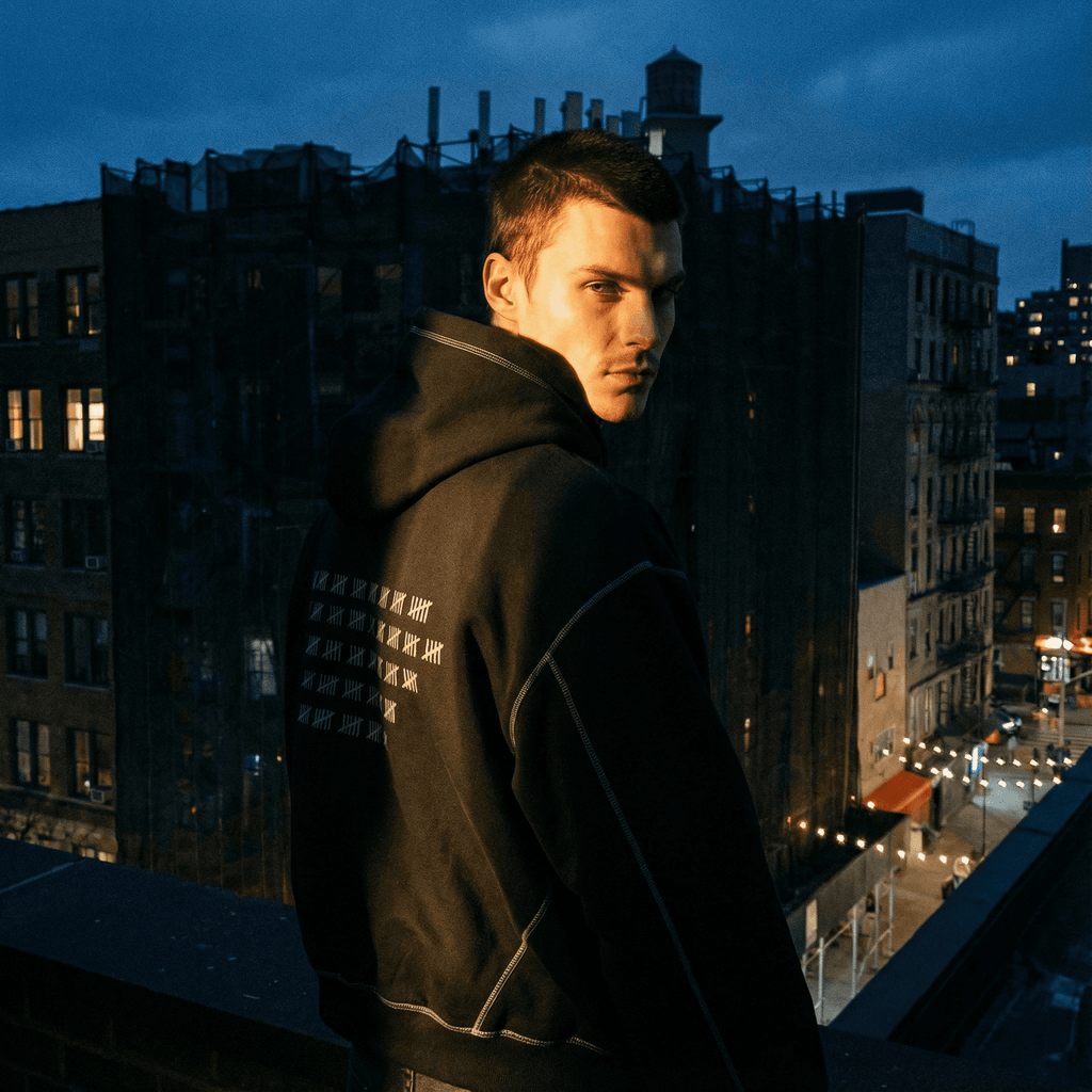 Man wearing FETISHISTO heavyweight fleece fetish hoodie with hood up in urban nighttime setting