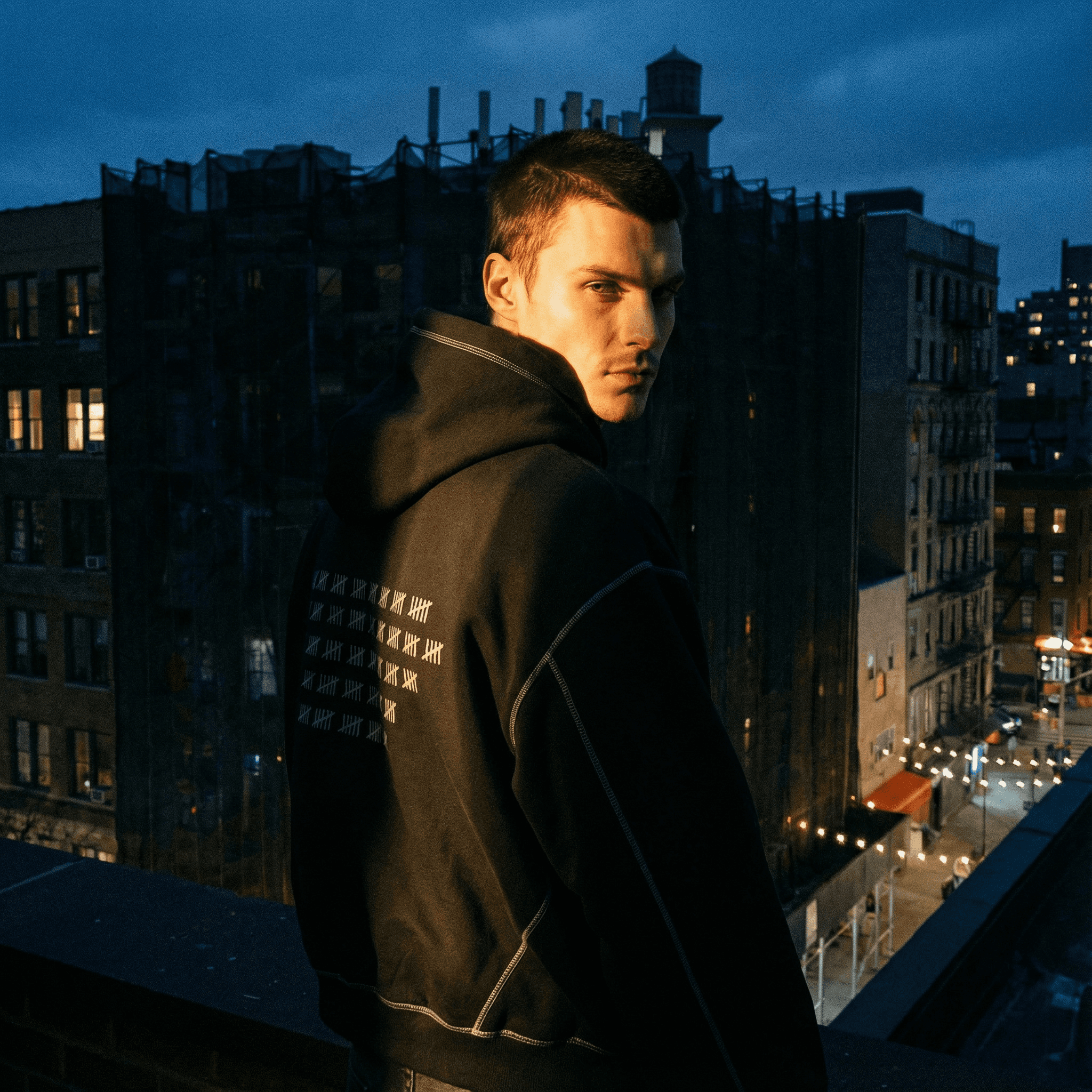 Man wearing FETISHISTO heavyweight fleece fetish hoodie with hood up in urban nighttime setting