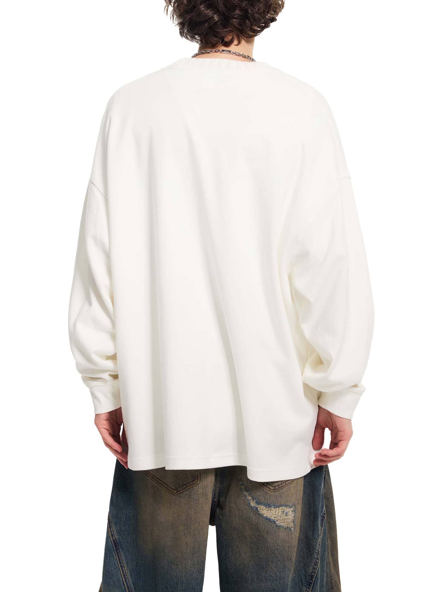 Back view of a person wearing a white oversize knitted round neck sweatshirt with cuffed sleeves