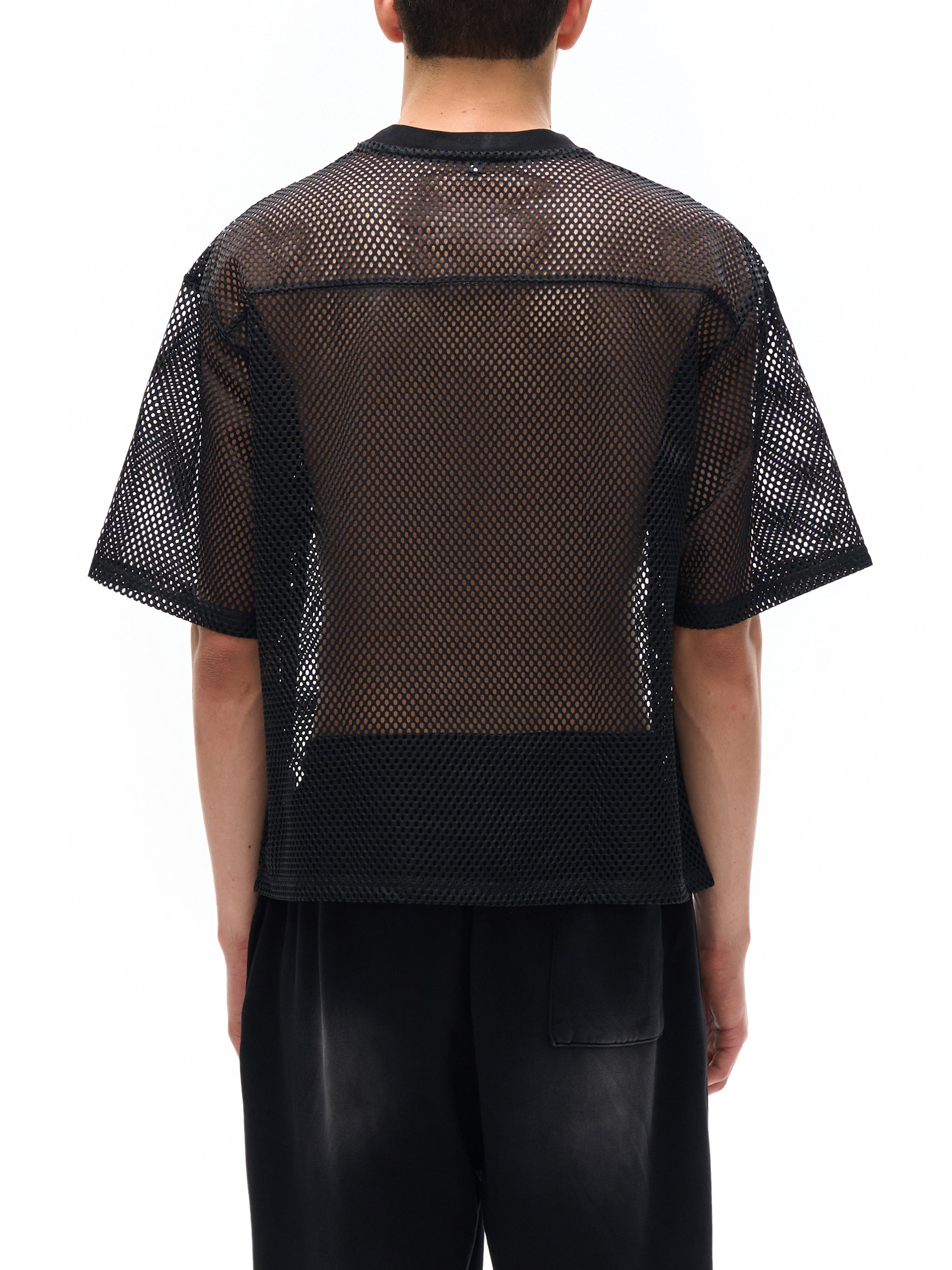 Back view of person wearing black see-through mesh t-shirt by ODMPOD with short sleeves