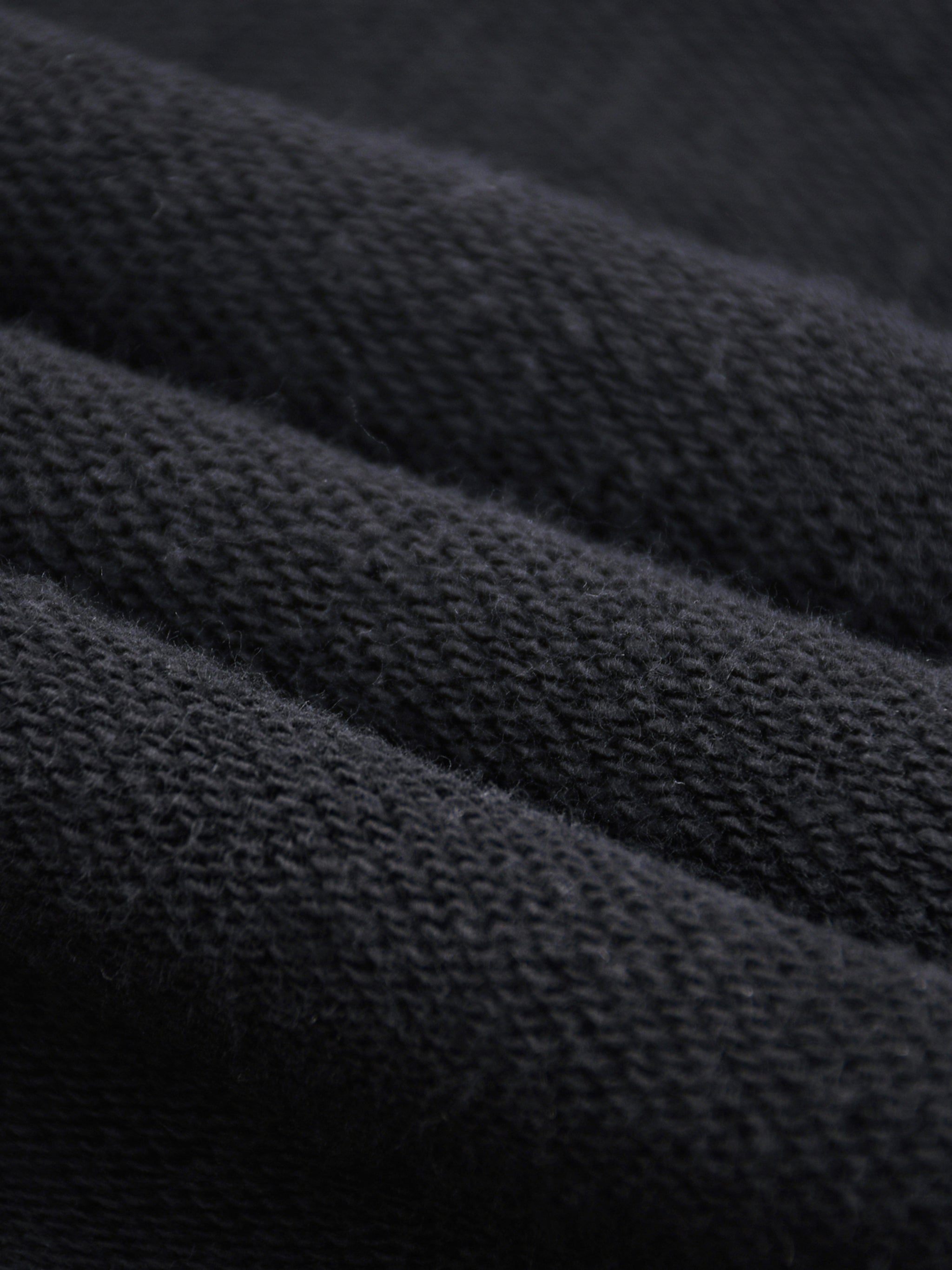 Close-up texture of black fabric from snow washed sweatpants for men by FETISHISTO