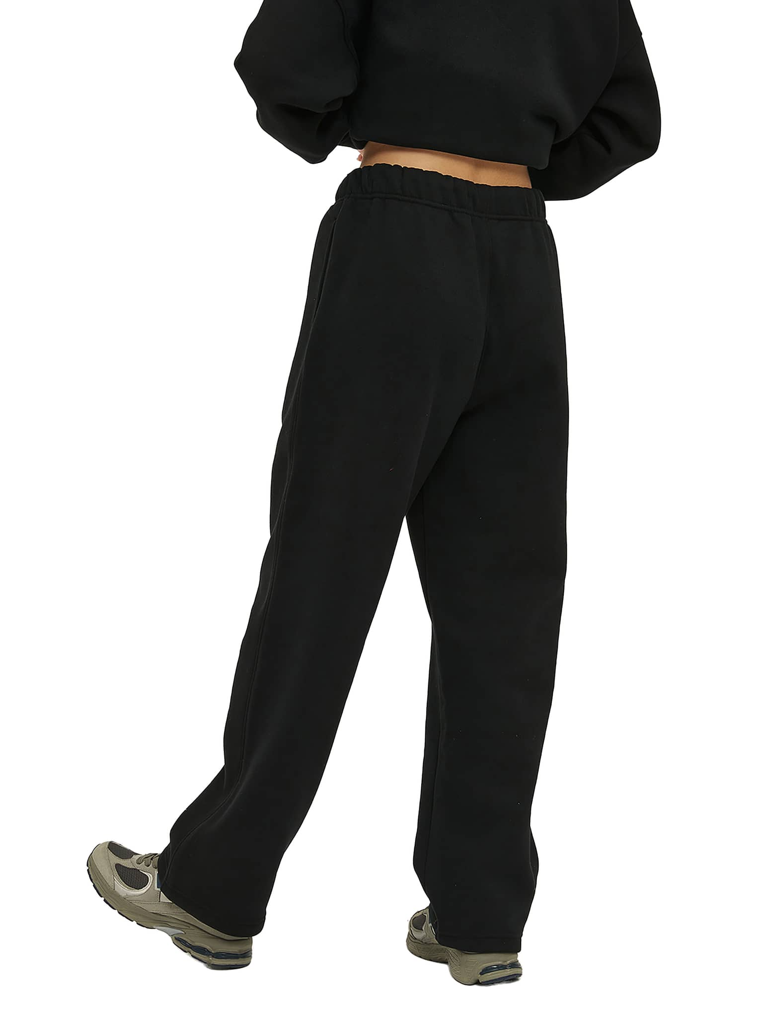 Black unisex fleece straight leg pants with elastic waist worn with black top and sneakers