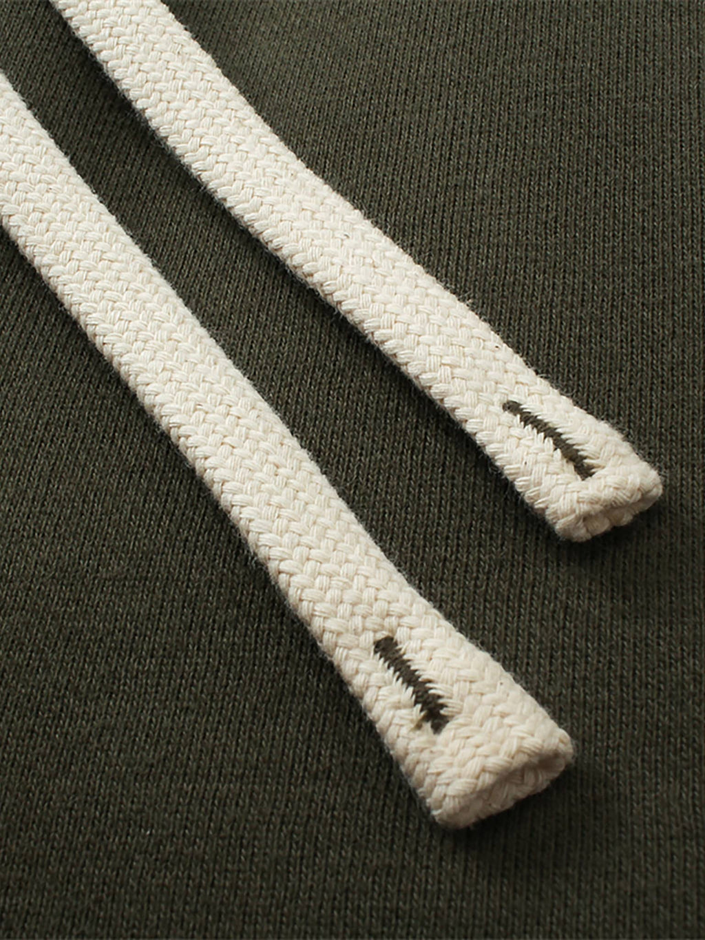 Close-up of beige drawstrings on olive fabric unisex fleece straight leg pants by FETISHISTO