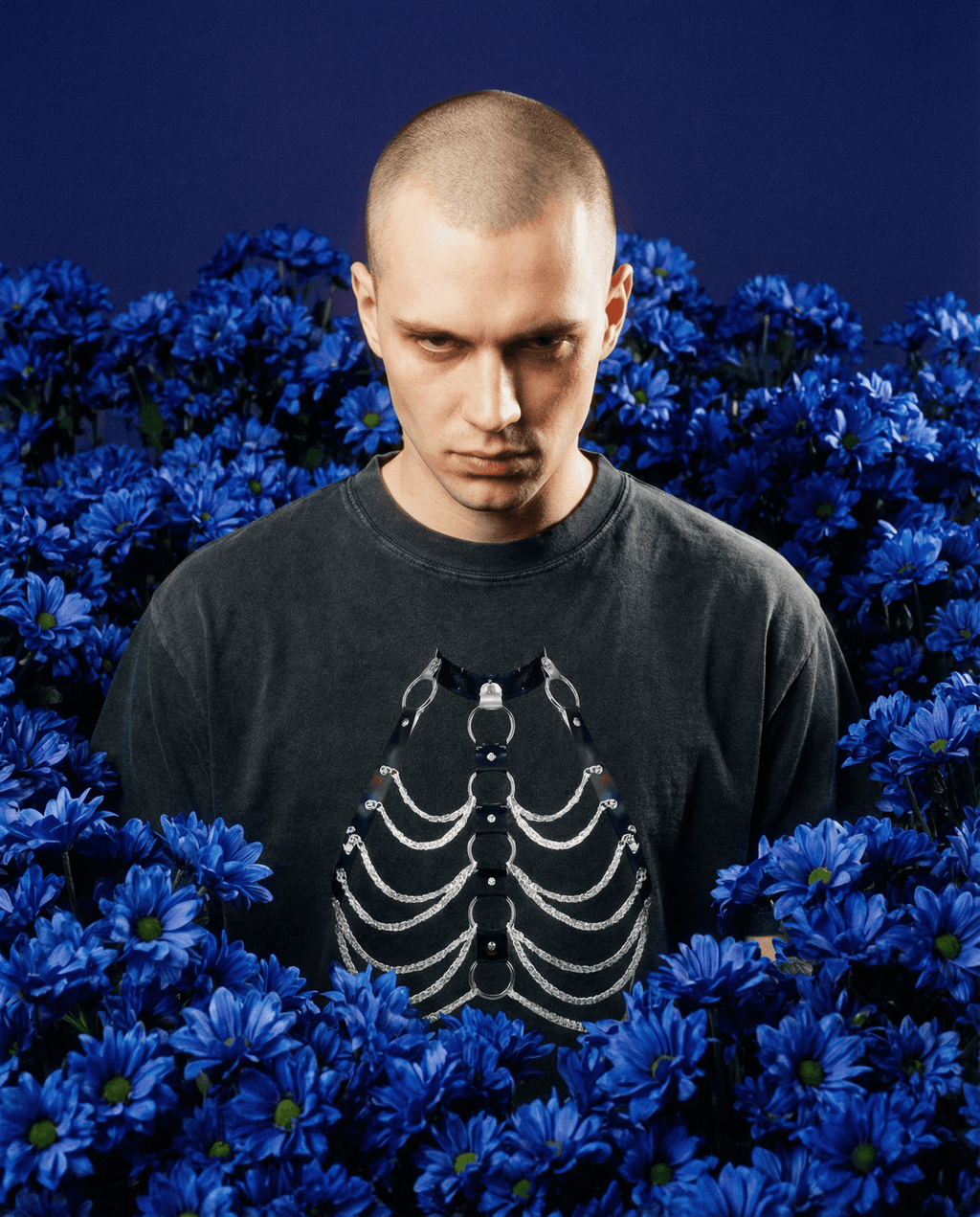 Man wearing black vintage wash boxy t-shirt with chain skeleton design surrounded by blue flowers