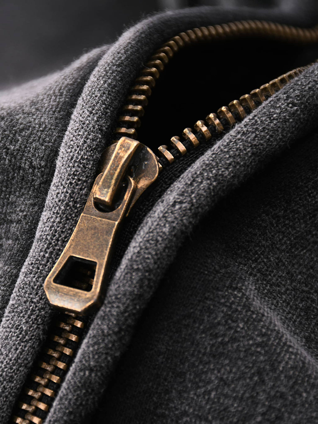 Close-up of bronze zipper on black fabric of zip through boxy fleece hoodie by FETISHISTO